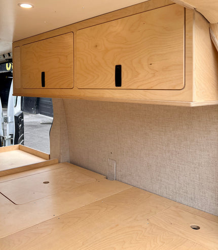 Wooden cabinets and countertop inside a camper van.