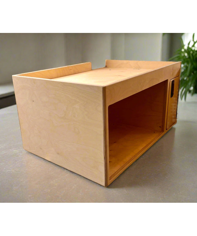 Wooden microwave cabinet on a concrete counter with a plant in the background