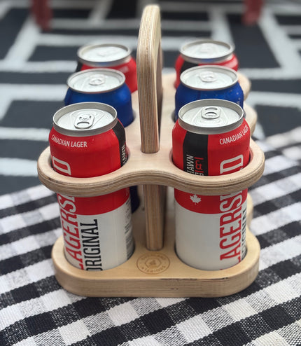 Wooden six-pack holder with craft beer cans on a checkered tablecloth