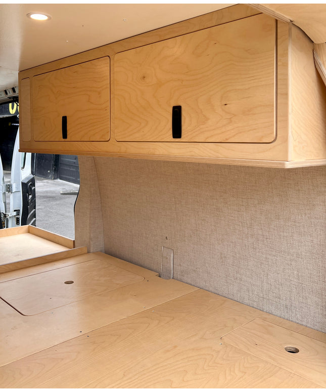 Wooden cabinets and countertop inside a camper van.