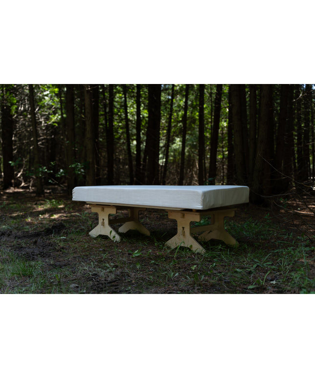Wooden bench with a cushion on top in a forest setting, essential gear for van life