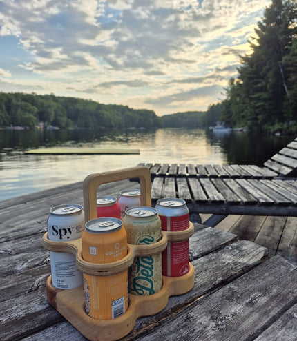 Six-pack holder with beer cans on a wooden dock by a lake