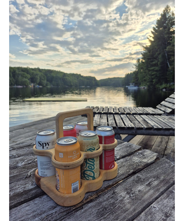 Six-pack holder with beer cans on a wooden dock by a lake