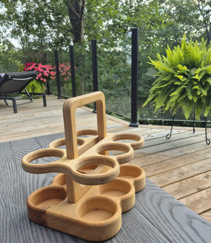 Plywood beer carrier on a table outdoors with greenery in the background