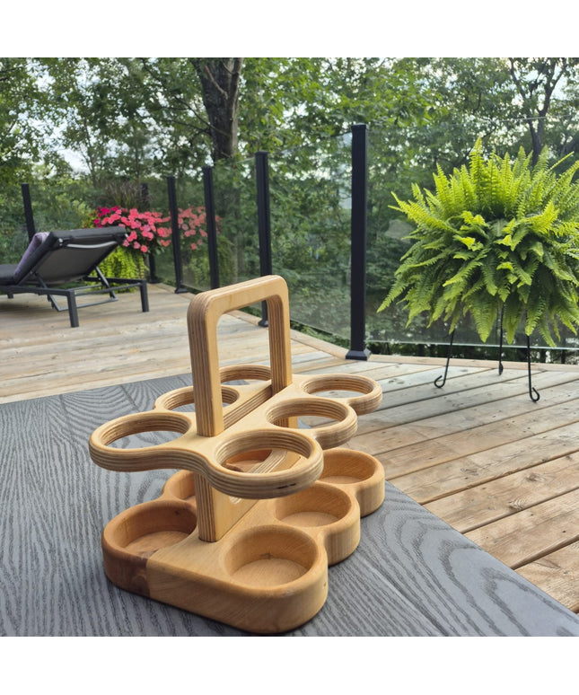Plywood beer carrier on a table outdoors with greenery in the background