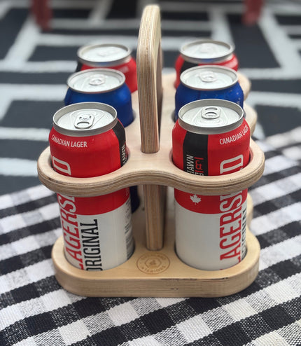 Wooden six-pack holder with beer cans on a checkered tablecloth