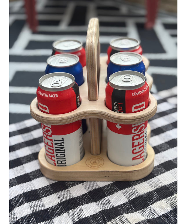 Wooden six-pack holder with beer cans on a checkered tablecloth