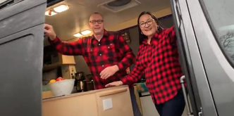 Couple standing inside a custom camper van conversion built by Overland Interiors