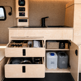 Front view of Overland Interiors 36-inch kitchenette in a low-roof van, showing organized kitchen storage, cookware drawers, and fresh and grey water storage.