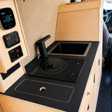 Overland Interiors 36-inch kitchenette in a low-roof van featuring a black countertop, induction cooktop, sink and integrated storage.