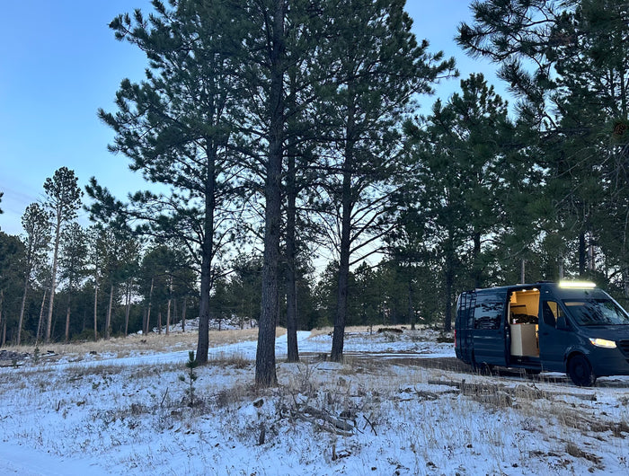 Van parked in a snowy forest at dusk