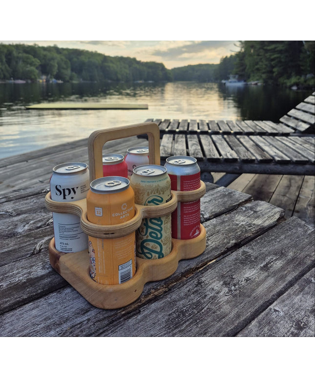 Six-pack holder with beer cans on a wooden dock by a lake