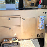 Installed 36-inch kitchen cabinet for high and low roof camper van conversion with integrated storage, countertop, and utility access by Overland Interiors.