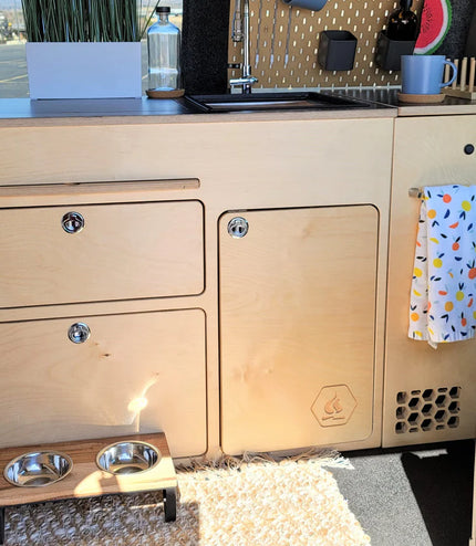 Installed 36-inch kitchen cabinet for high and low roof camper van conversion with integrated storage, countertop, and utility access by Overland Interiors.