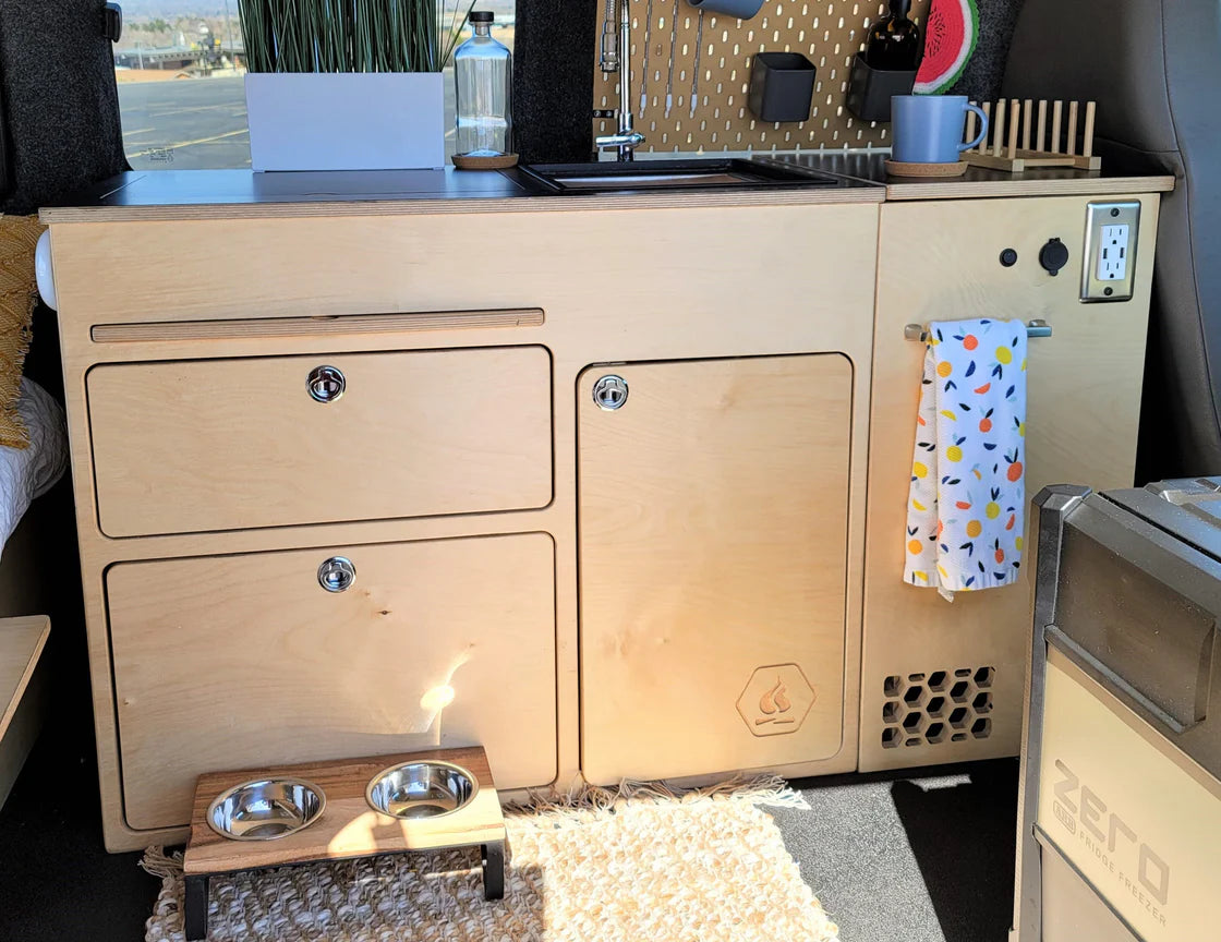 Installed 36-inch kitchen cabinet for high and low roof camper van conversion with integrated storage, countertop, and utility access by Overland Interiors.