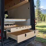 Rear pull-out storage drawer system installed inside a camper van conversion for organized gear and cargo storage by Overland Interiors