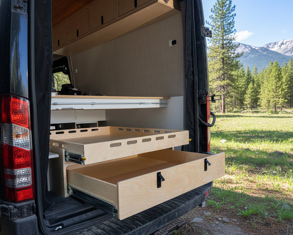 Rear pull-out storage drawer system installed inside a camper van conversion for organized gear and cargo storage by Overland Interiors
