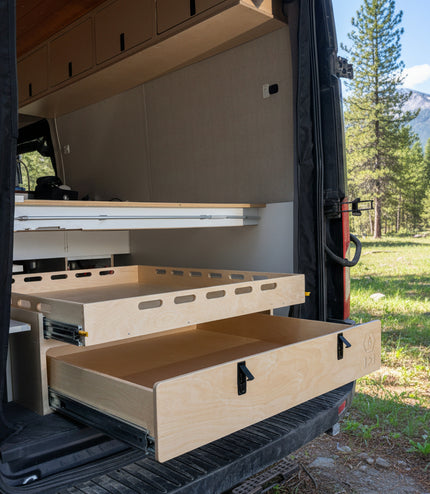 Rear pull-out storage drawer system installed inside a camper van conversion for organized gear and cargo storage by Overland Interiors
