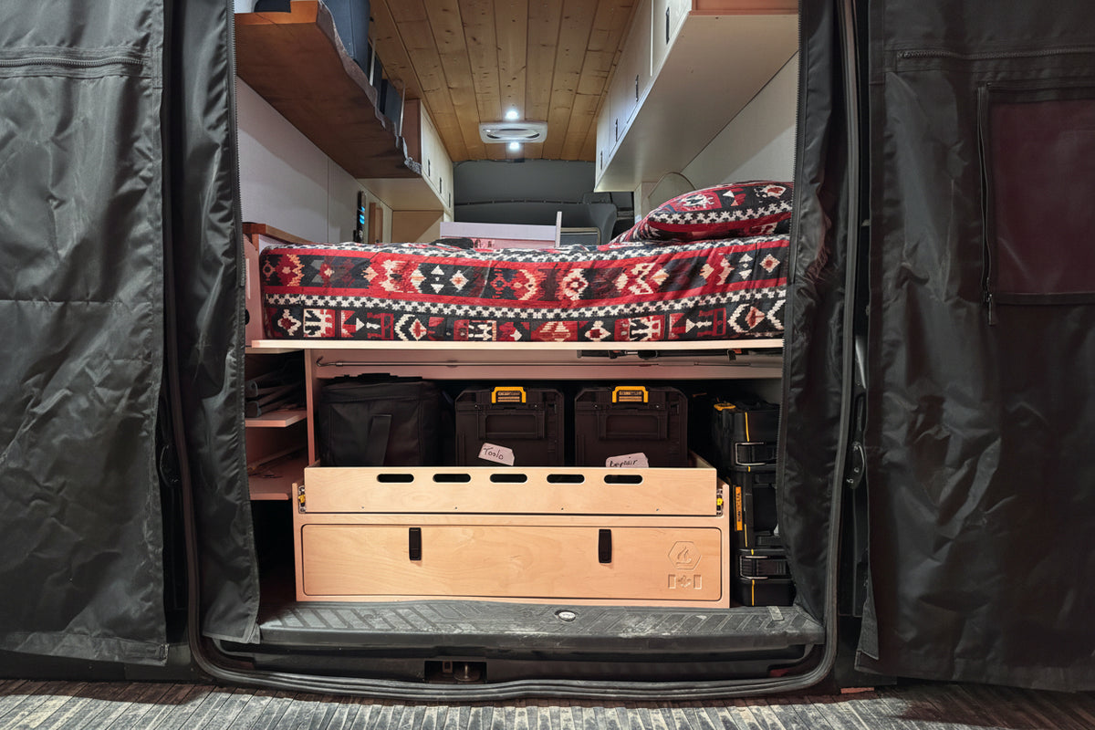 Rear camper van storage drawer and cargo organizer system with pull-out tray and integrated gear storage by Overland Interiors.
