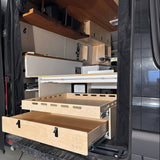 Installed rear pull-out storage drawer system inside a camper van conversion with sliding cargo tray and organized gear storage by Overland Interiors