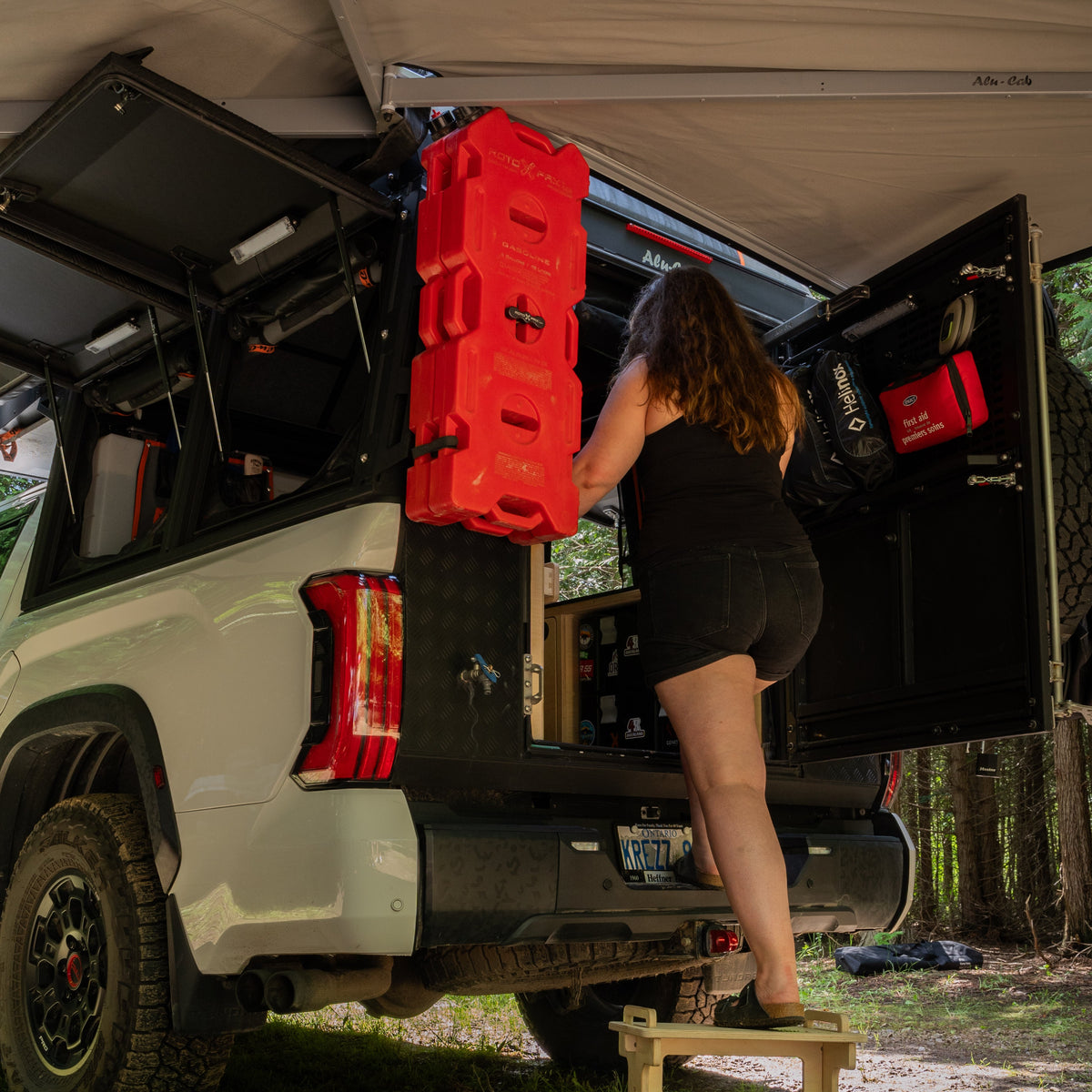 Flat pack camper van step stool in use beside an overland truck camper for easier vehicle access by Overland Interiors