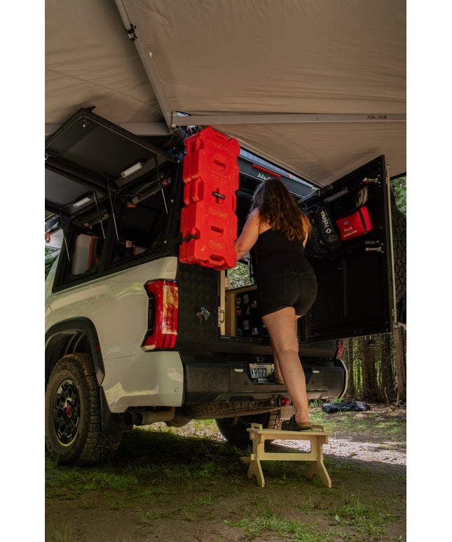 Flat pack camper van step stool in use beside an overland truck camper for easier vehicle access by Overland Interiors