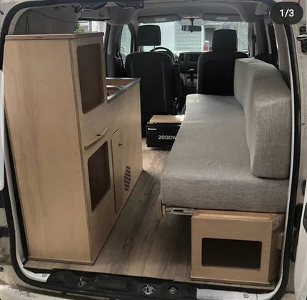Installed compact camper van kitchenette with integrated sink cabinet and bench seating inside a modular van conversion by Overland Interiors.