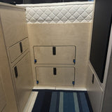Custom garage access panel with integrated storage doors beneath the raised bed in a Mercedes Sprinter 144 camper van.