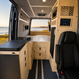 Full interior view of a custom Mercedes Sprinter 144 camper van  by Overland Interiors, with modular kitchenette, fridge cabinet, raised bed platform 