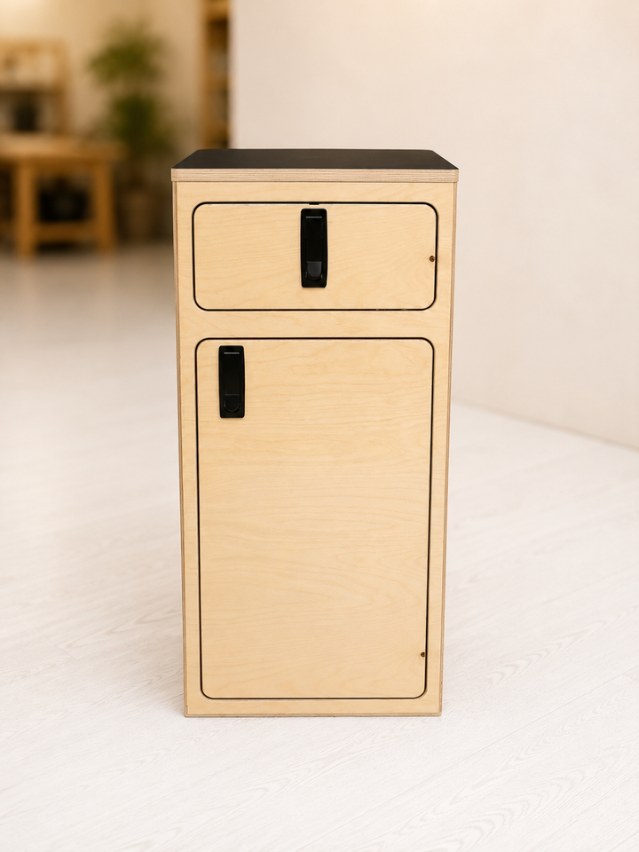 Front view of the Overland Interiors One+One Base Cabinet in birch plywood with upper drawer, lower storage cabinet, black compression latches and black laminate top