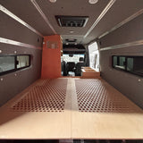 Raised bed platform with honeycomb ventilation panels inside a custom Mercedes Sprinter 144 camper van conversion.