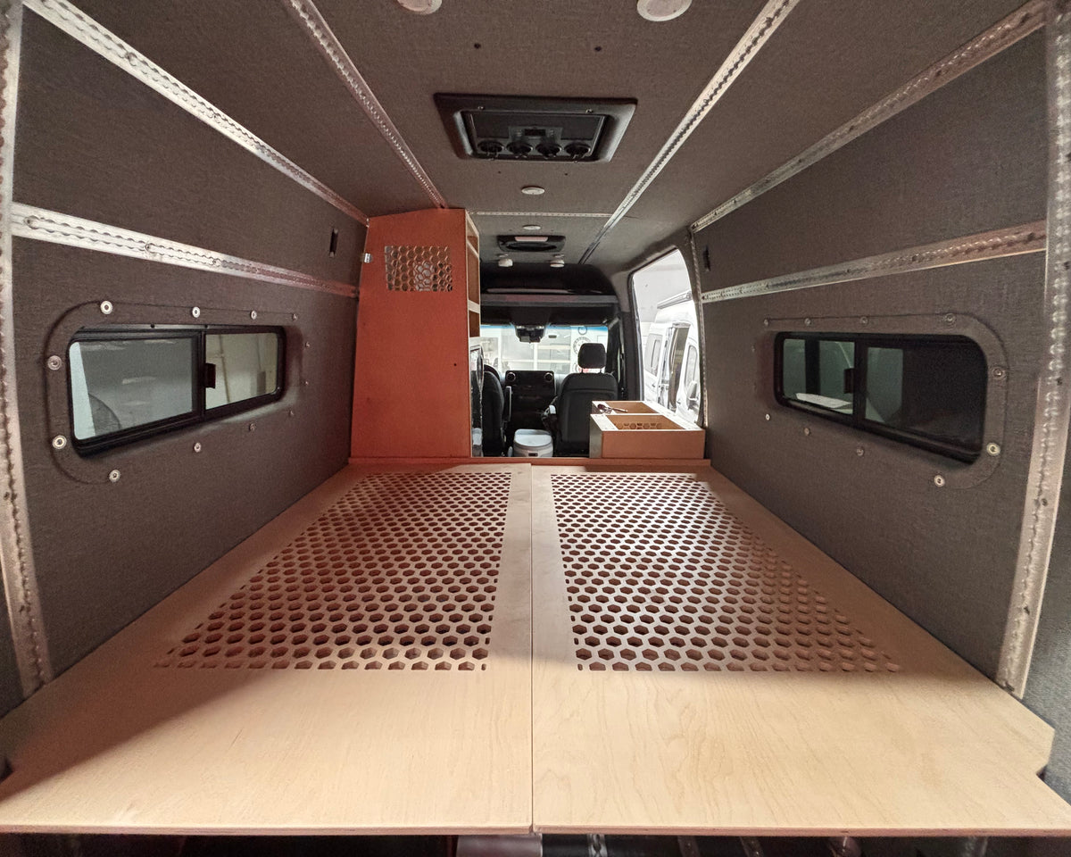Raised bed platform with honeycomb ventilation panels inside a custom Mercedes Sprinter 144 camper van conversion.