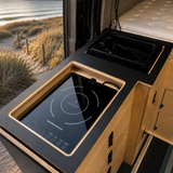 custom kitchenette featuring a black laminate countertop, integrated induction cooktop and sink inside a Mercedes Sprinter 144 camper van by Overland Interiors