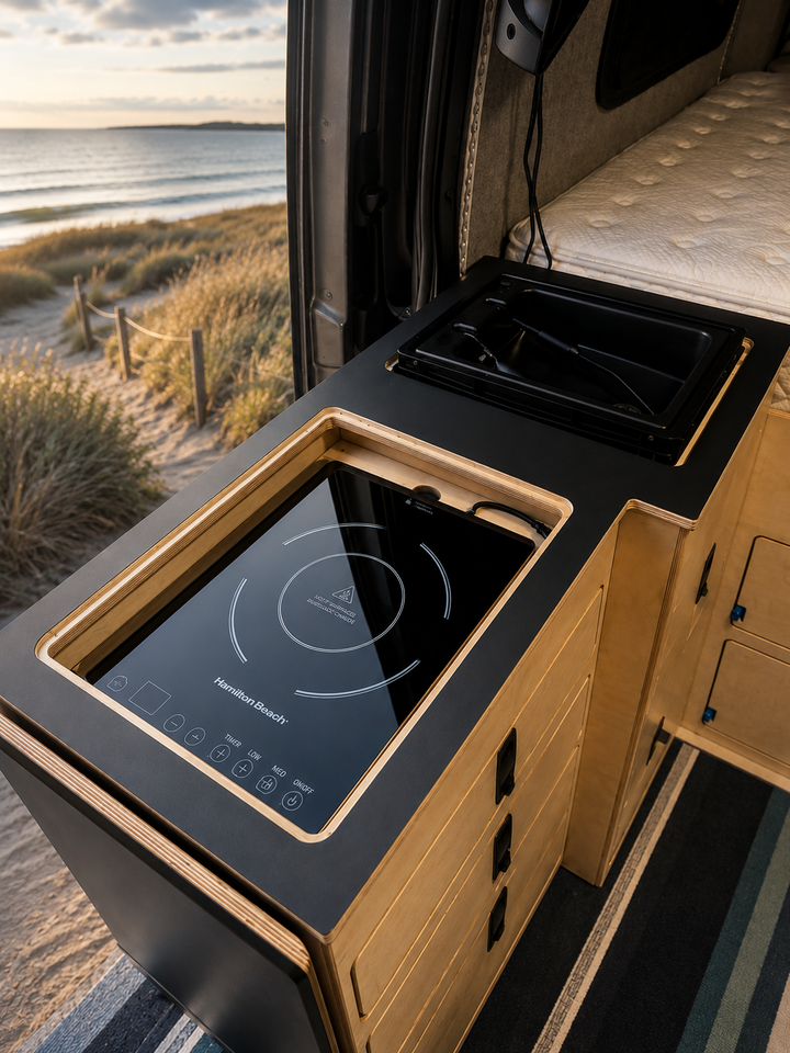 custom kitchenette featuring a black laminate countertop, integrated induction cooktop and sink inside a Mercedes Sprinter 144 camper van by Overland Interiors