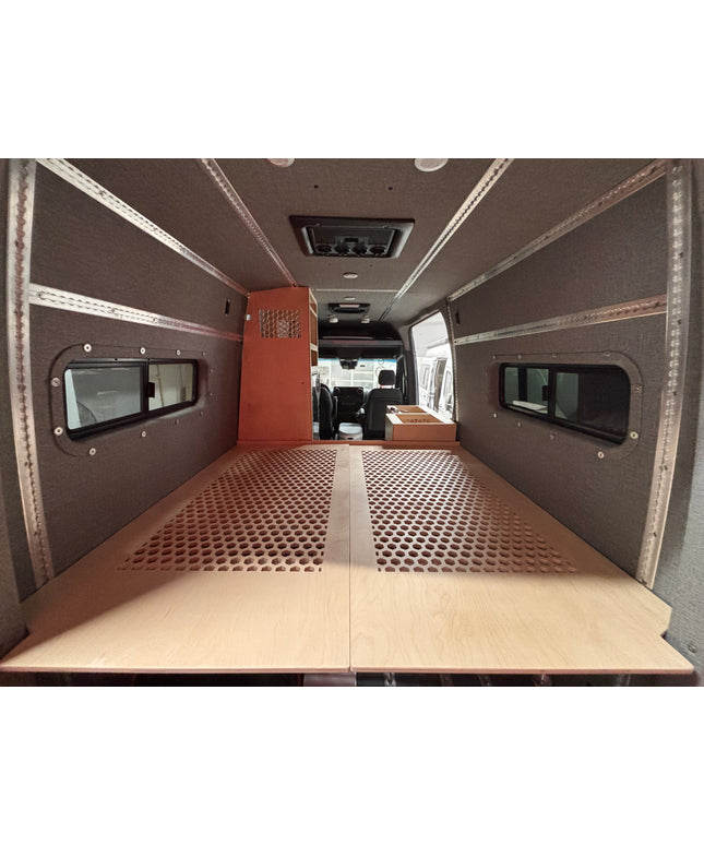 Interior of a van with a wooden bed platform and fabric walls with Ltrack mounts