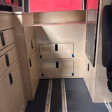 Van bed platform cover panel with integrated storage access doors in camper van