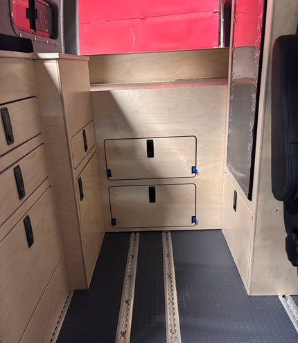 Van bed platform cover panel with integrated storage access doors in camper van