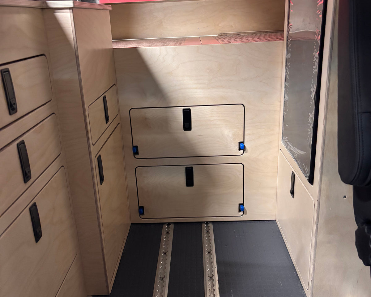 Van bed platform cover panel with integrated storage access doors in camper van