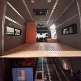 Interior of a van with a bed setup and small kitchen area.