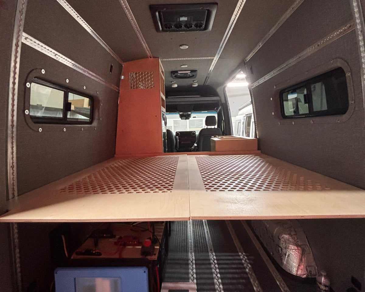 Interior of a van with a bed setup and small kitchen area.