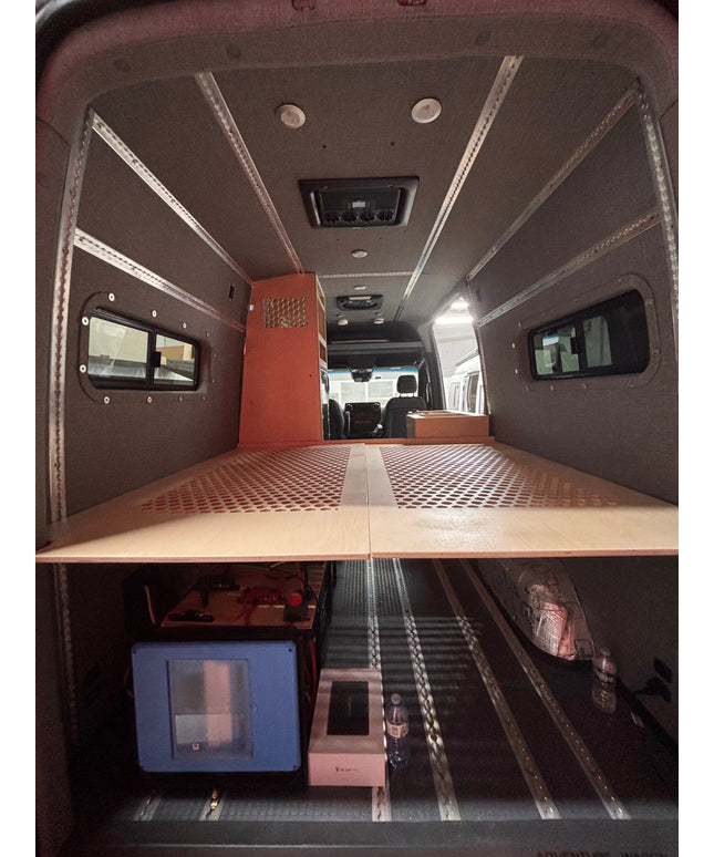 Interior of a van with a bed setup and small kitchen area.