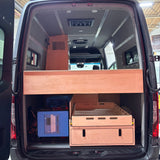 Van interior with wooden storage compartments and electronic equipment.
