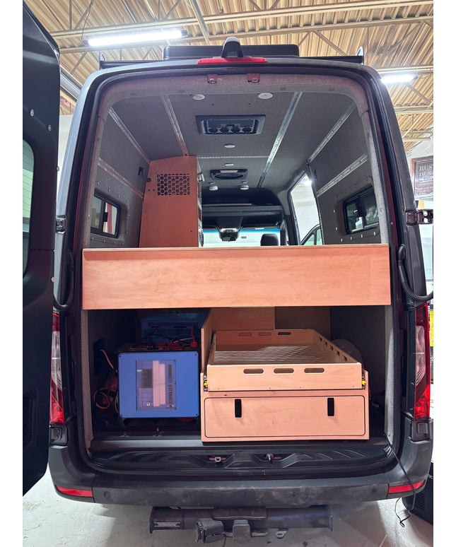 Van interior with wooden storage compartments and electronic equipment.